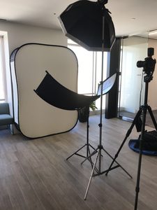 An image of a tripod, background, and portable lighting for headshots taken in an office lobby.