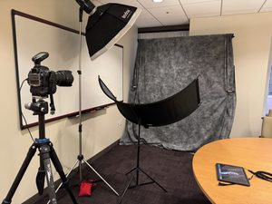 A camera, portable lighting and backdrop in a conference room for on-location headshots.