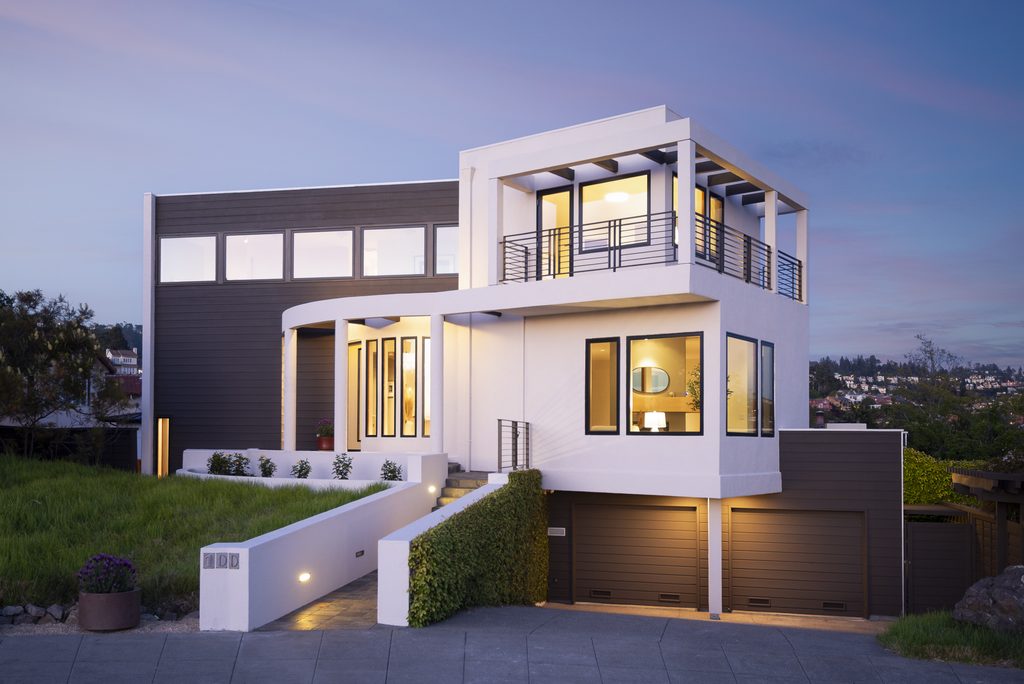 A modern style home with glowing windows at twilight.