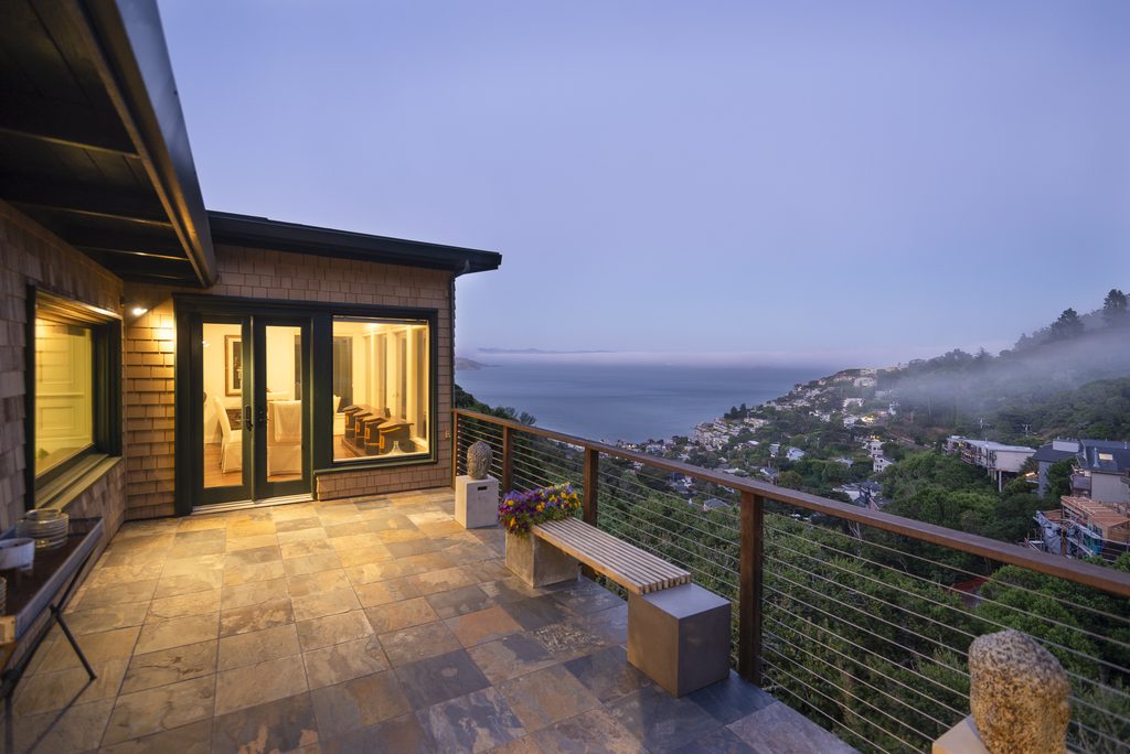 View from an outdoor patio of a home at twilight--looking out onto San Francisco Bay and the homes in Sausalito with fog.